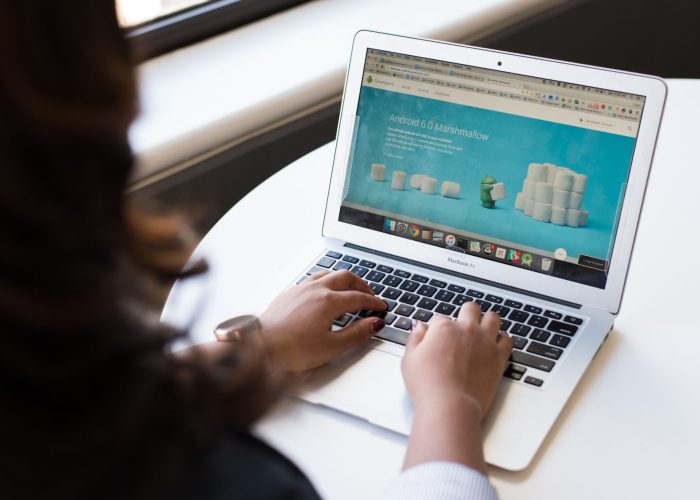 Businesswoman working on laptop with Android 6.0 Marshmallow webpage open.